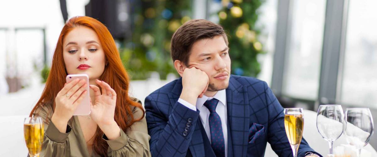 Bored man sitting next to woman at a table