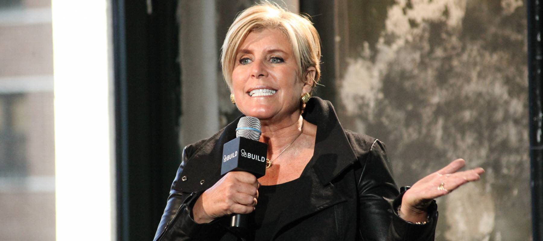 Thinking business woman with glasses looking up on many questions mark isolated on gray wall background