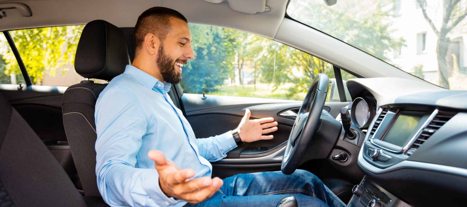 Side view of happy and surprised young businessman driving car.