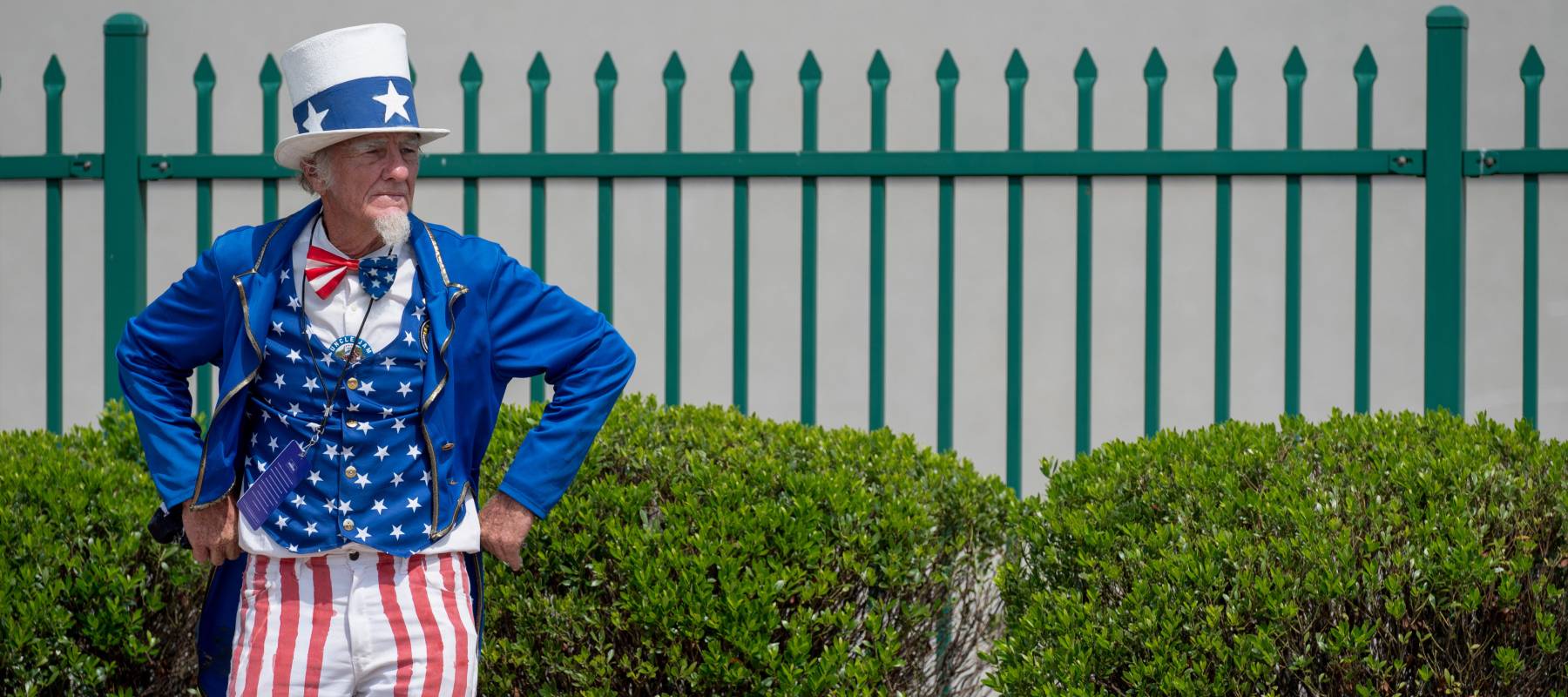 A man dressed as Uncle Sam waits outside of a Trump rally.