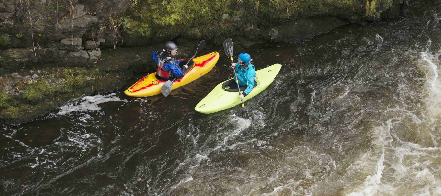 Two kayakers paddling rapids.