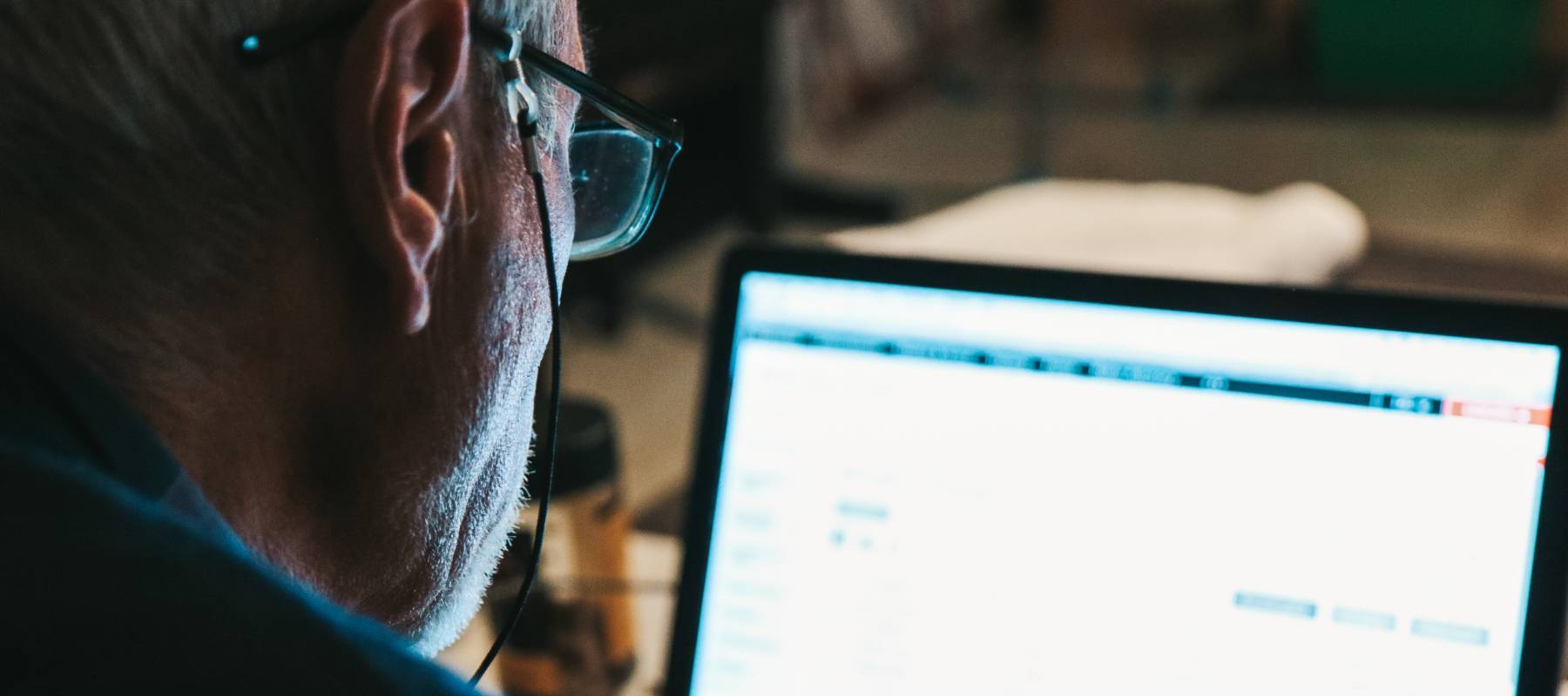 Old man watching the stock market at his laptop