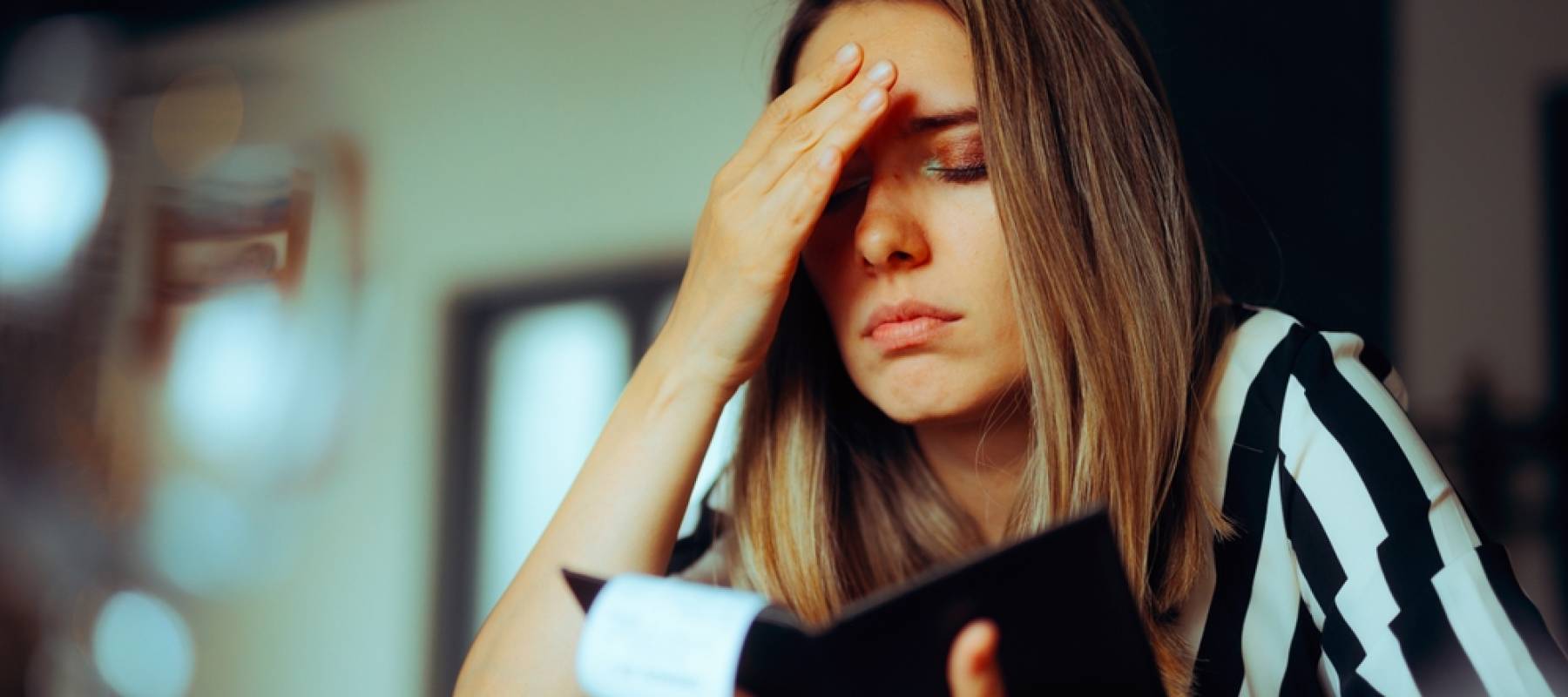 unhappy young Caucasian woman looking at her check book