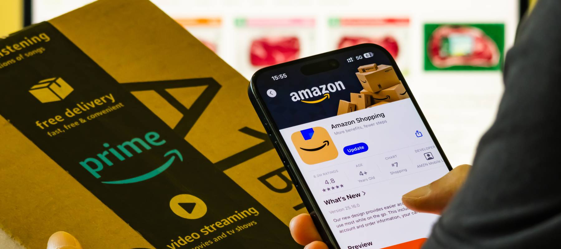 In this photo illustration, a person holds a smartphone displaying an Amazon app page in one hand and an Amazon Prime delivery box in the other hand in Chongqing, China, Aug. 22, 2025.