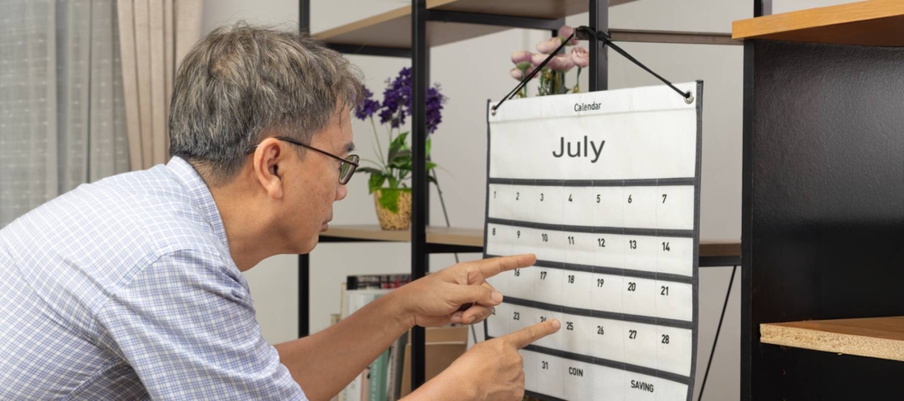confused older Asian man pointing at a calendar