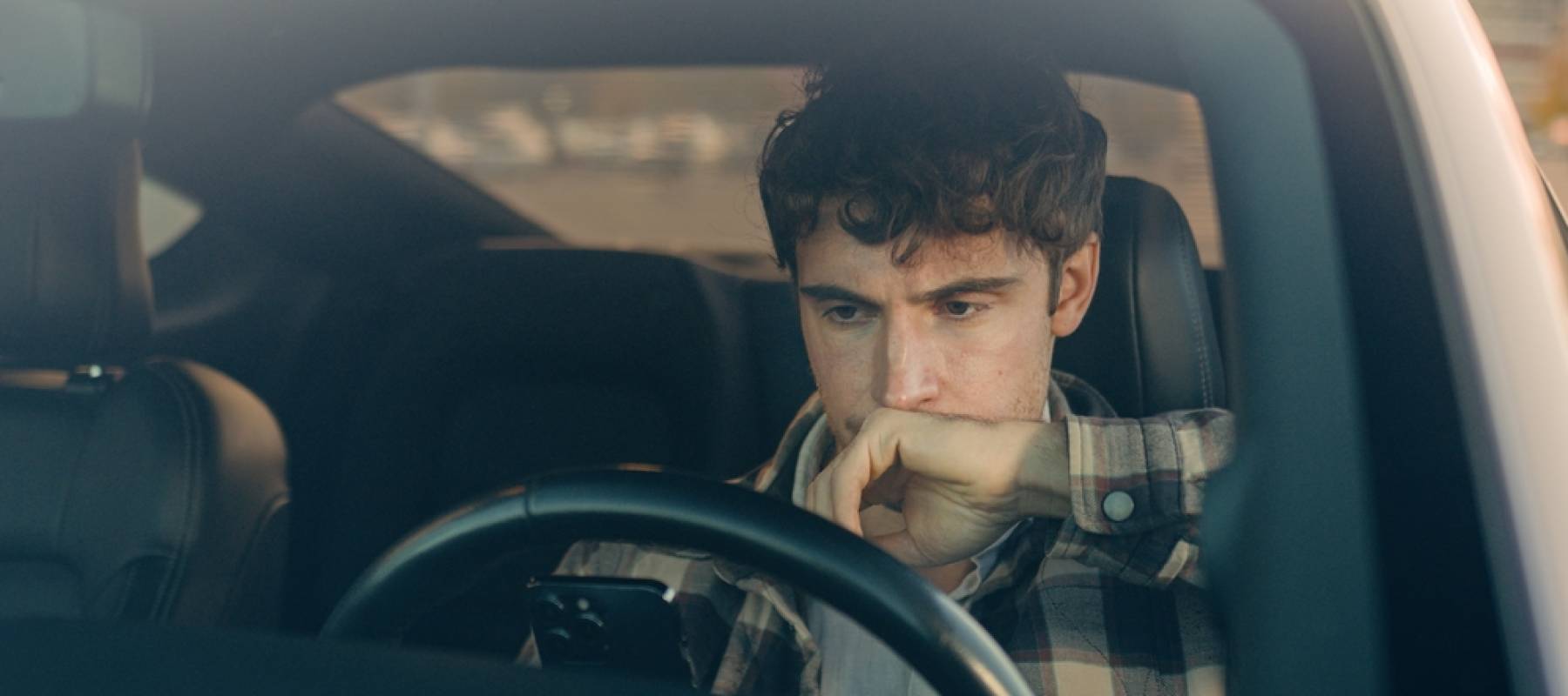 a young Caucasian looking upset in his car