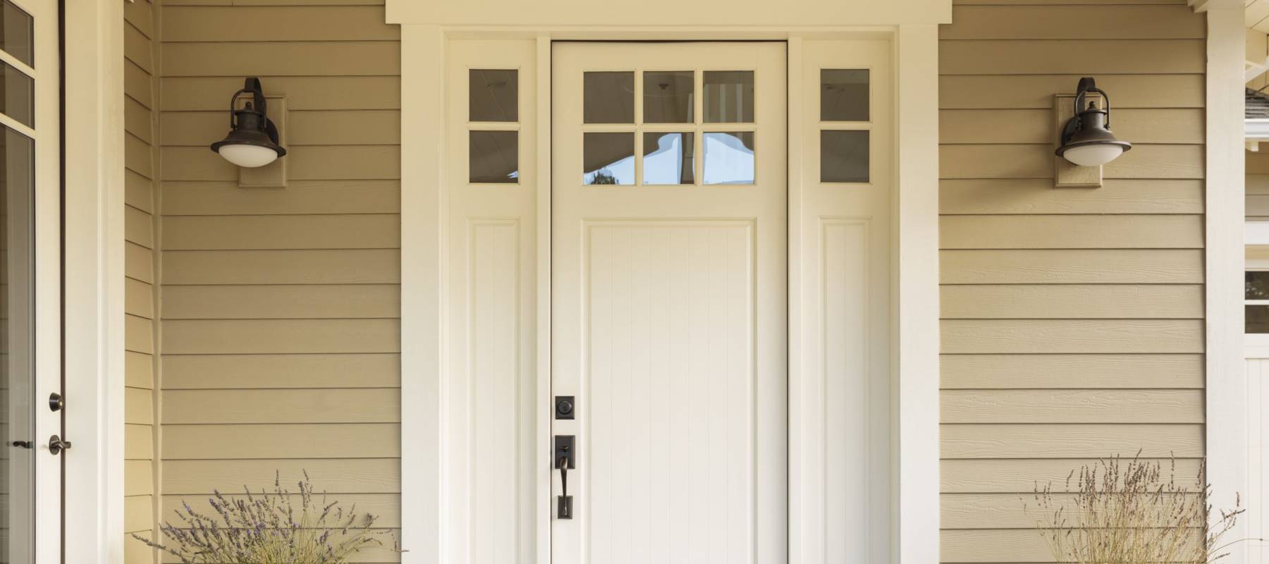 White front door with small square decorative windows and flower pots