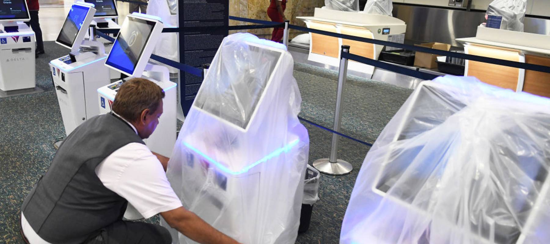 Delta Airlines employee Juan Martinez covers a check-in kiosk with a protective plastic bag at Orlando International Airpor