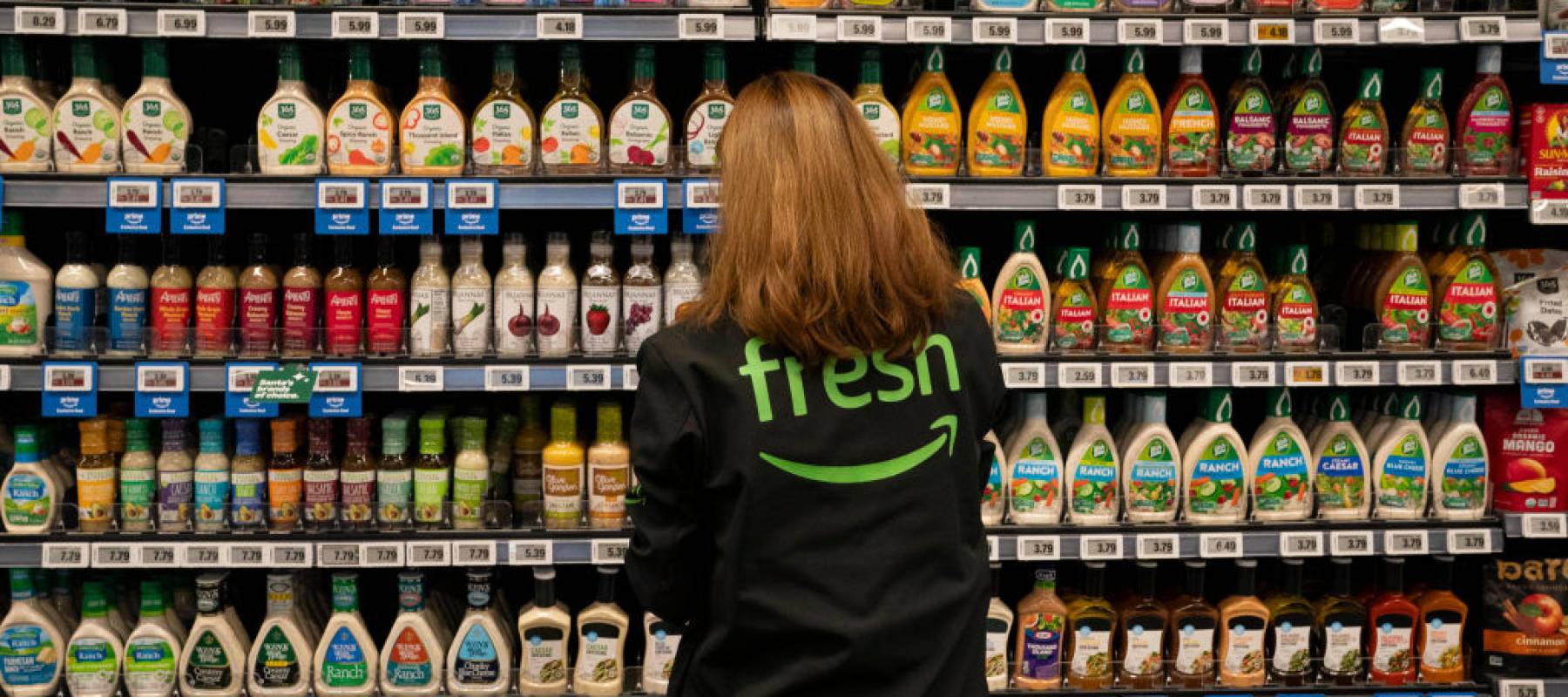 n employee arranges a salad dressing display at an Amazon Fresh grocery store on December 12, 2024