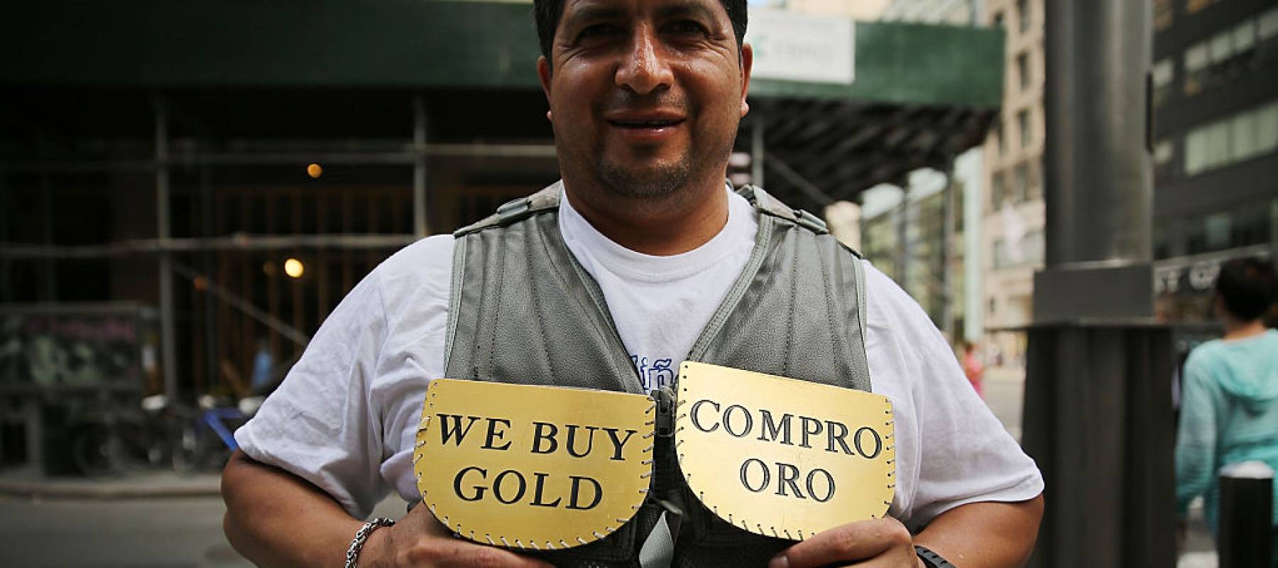 Man holding 'we buy gold' sign.