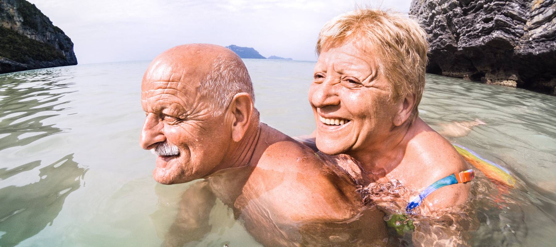 An older couple swimming while on vacation.