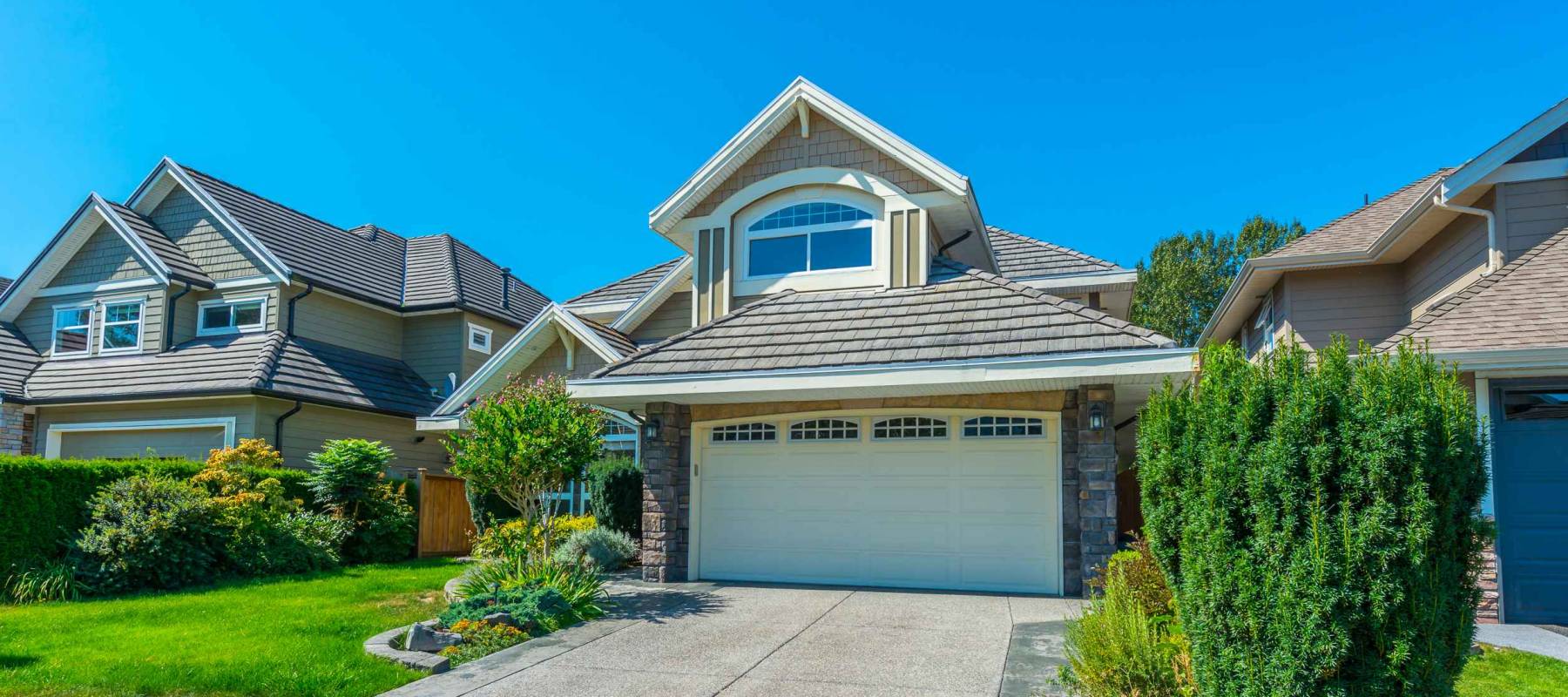 Big custom made luxury house with nicely landscaped and trimmed front yard and driveway to garage.