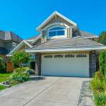 Big custom made luxury house with nicely landscaped and trimmed front yard and driveway to garage.