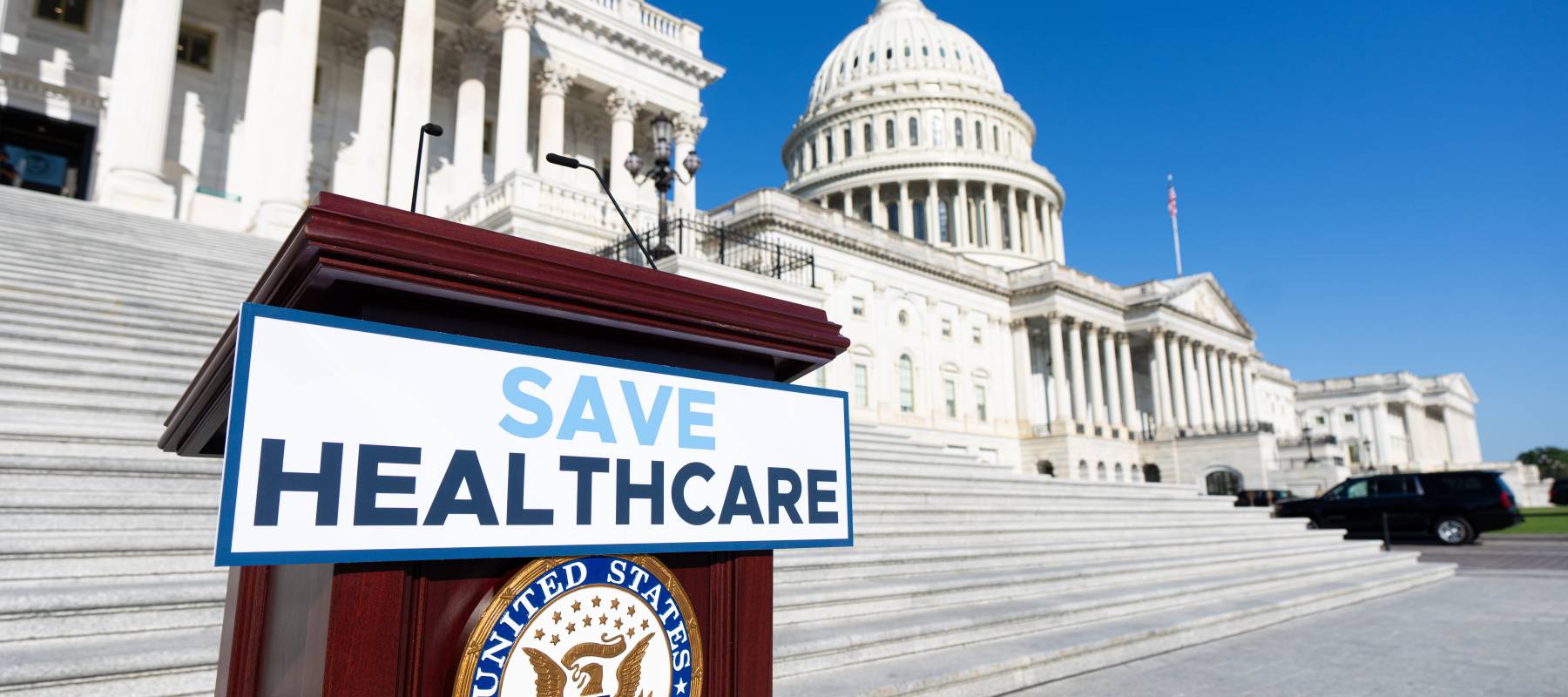 A "Save Healthcare" sign is placed on the podium for the House Democrats' news conference.