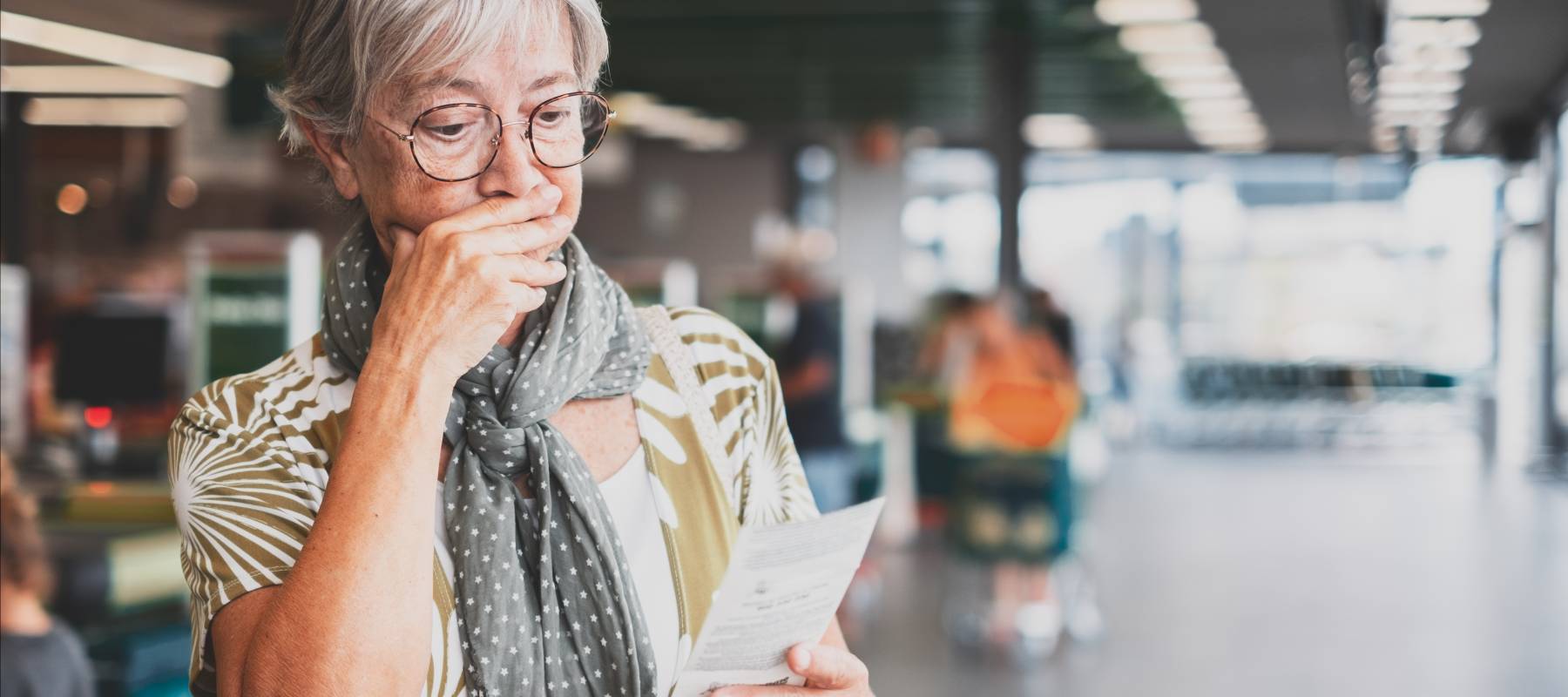 Woman looking with shock at grocery receipt.