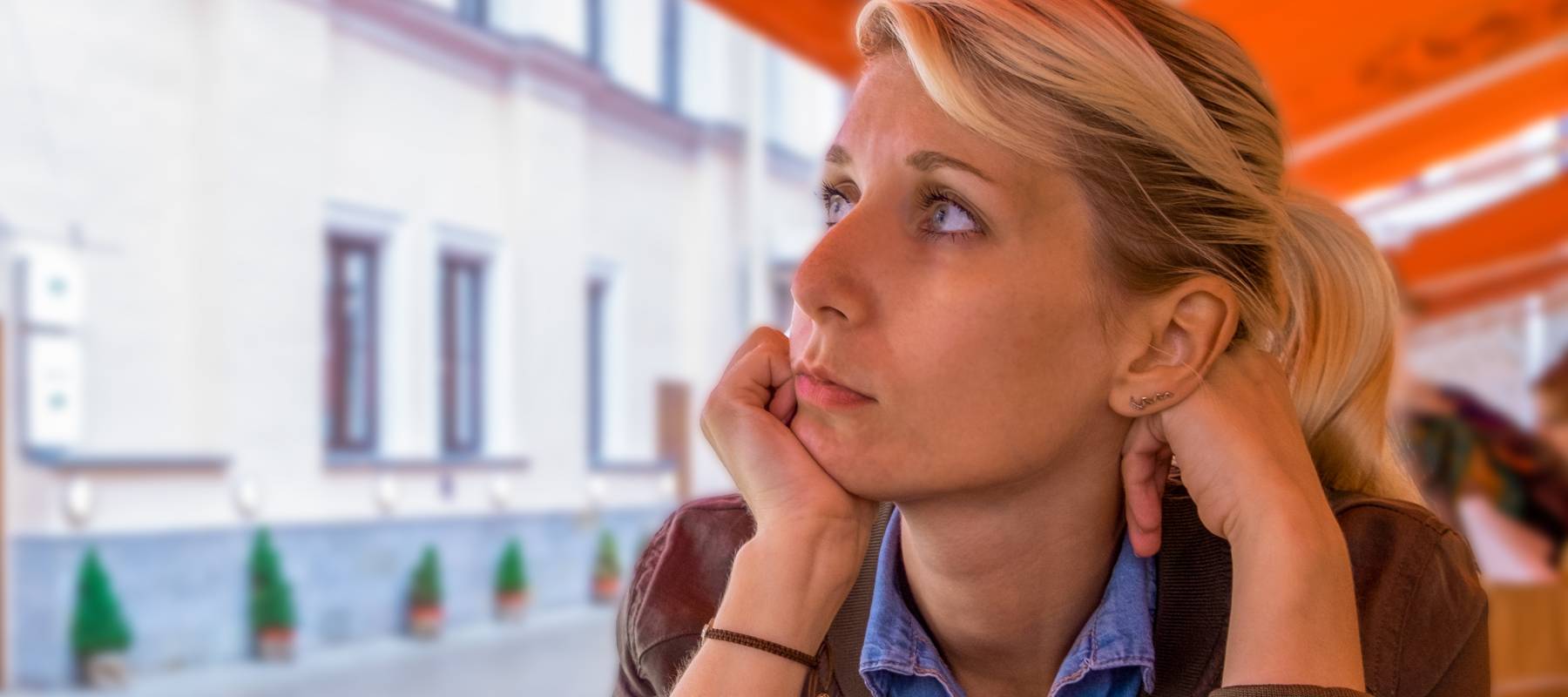 A woman sitting on a patio, staring into the distance.