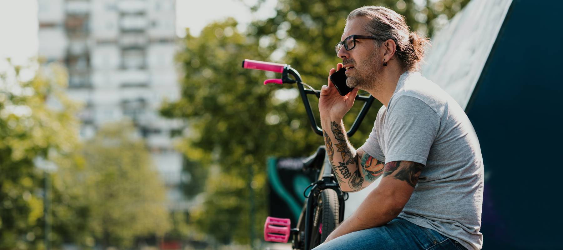 middle aged man with tattoos talks on the phone outdoors