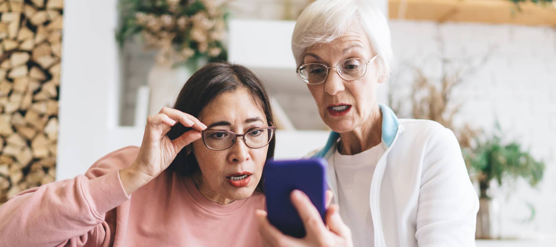A woman shares what's on her mobile device with her friend.