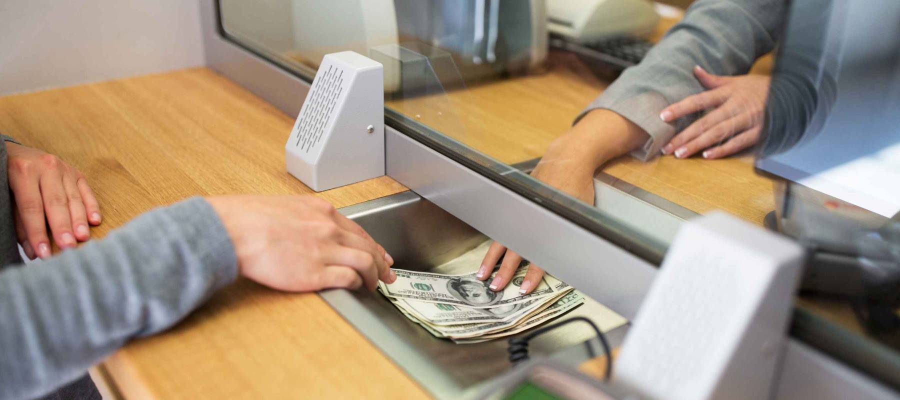 people, withdrawal, saving and finance concept - clerk giving cash money to customer at bank office or currency exchanger