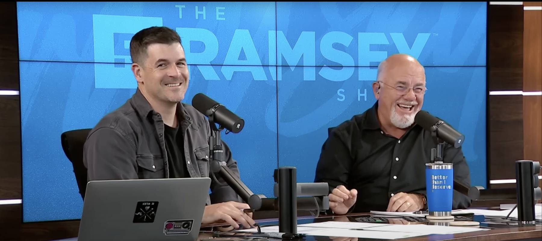 Dave Ramsey and co-host laugh on the set of their show