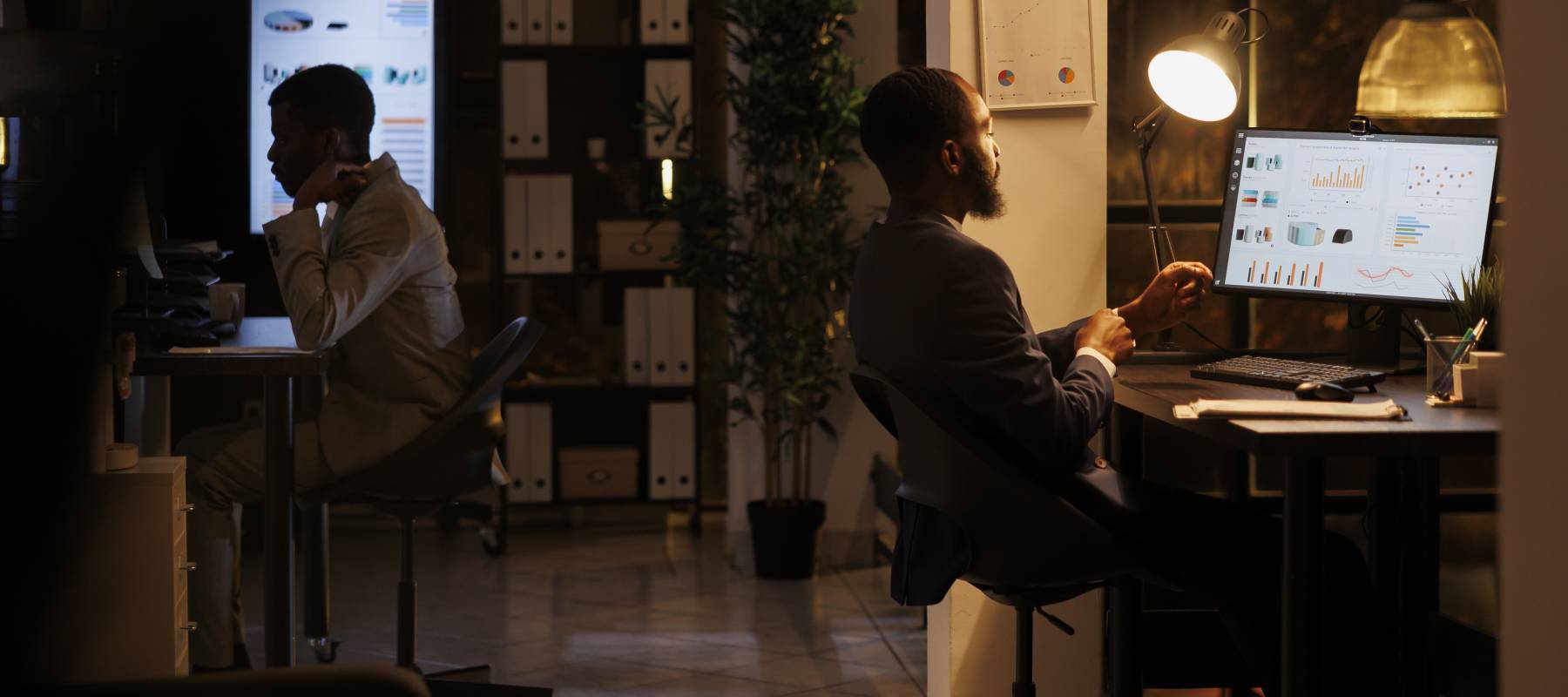 Two people working on computers in an office at night.