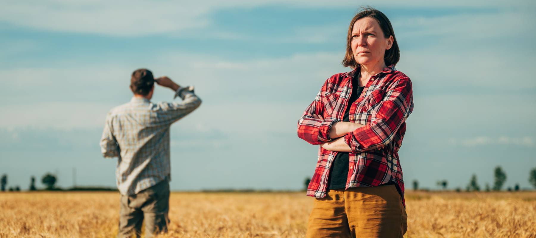 Male and female farmers posing in ripe wheat plantation field ready for harvest.