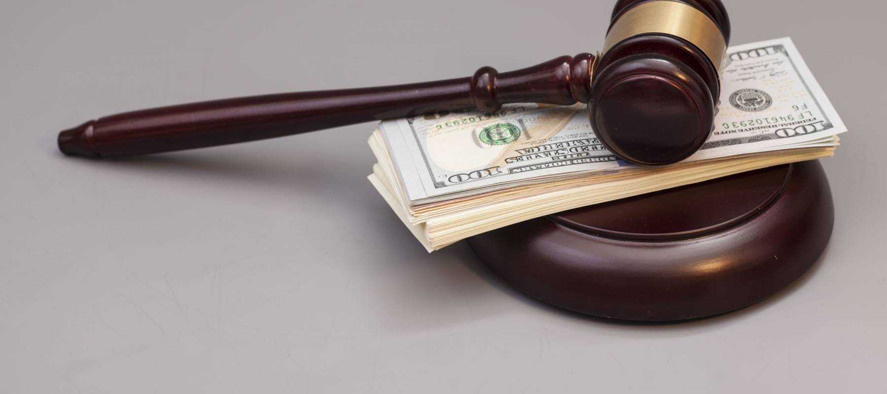 Law gavel on a stack of dollars isolated on gray background