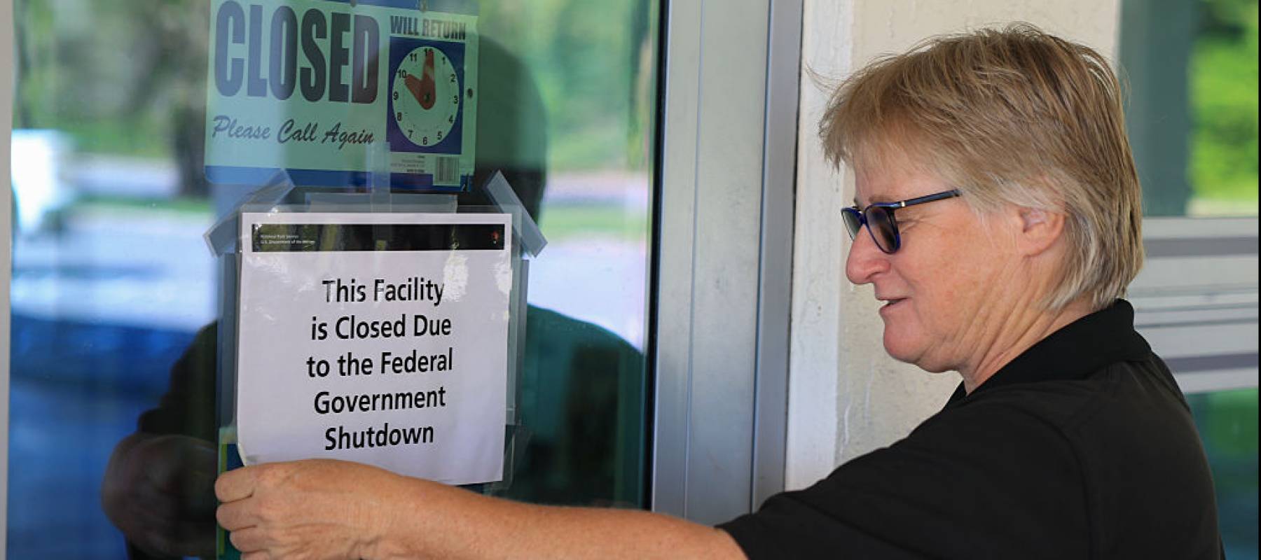Woman putting closed sign on door.