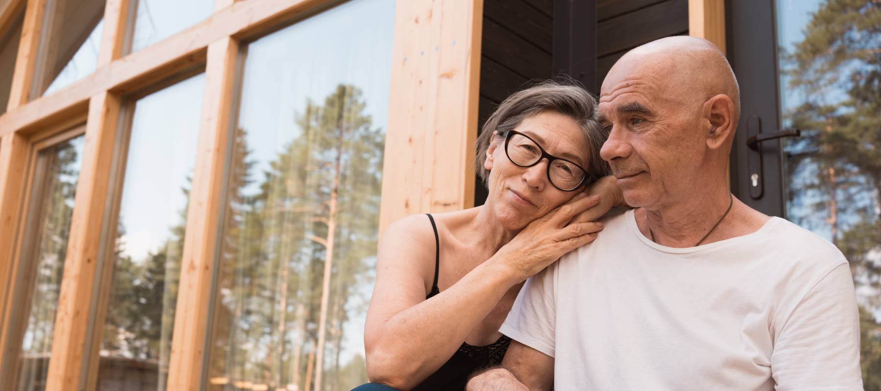 senior couple hugging and smiling while sitting on the terrace at home
