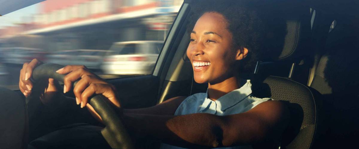 Portrait of smiling young african american woman driving a car