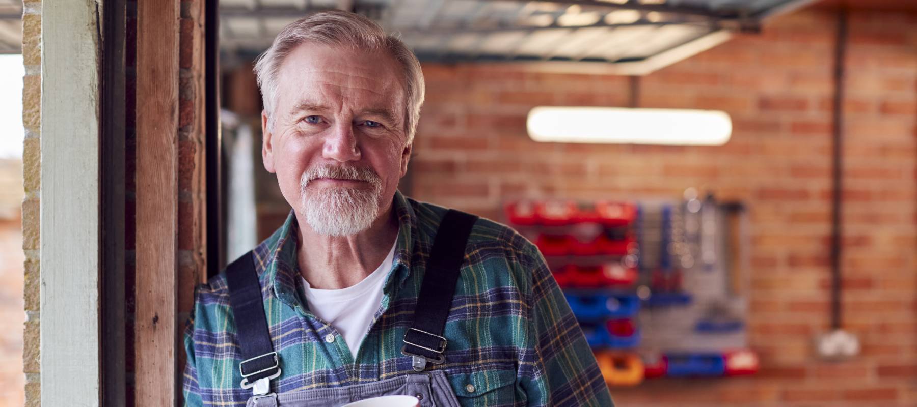 A man in overalls working in a garage.