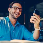 Young male investor wearing glasses checking stocks on his smartphone