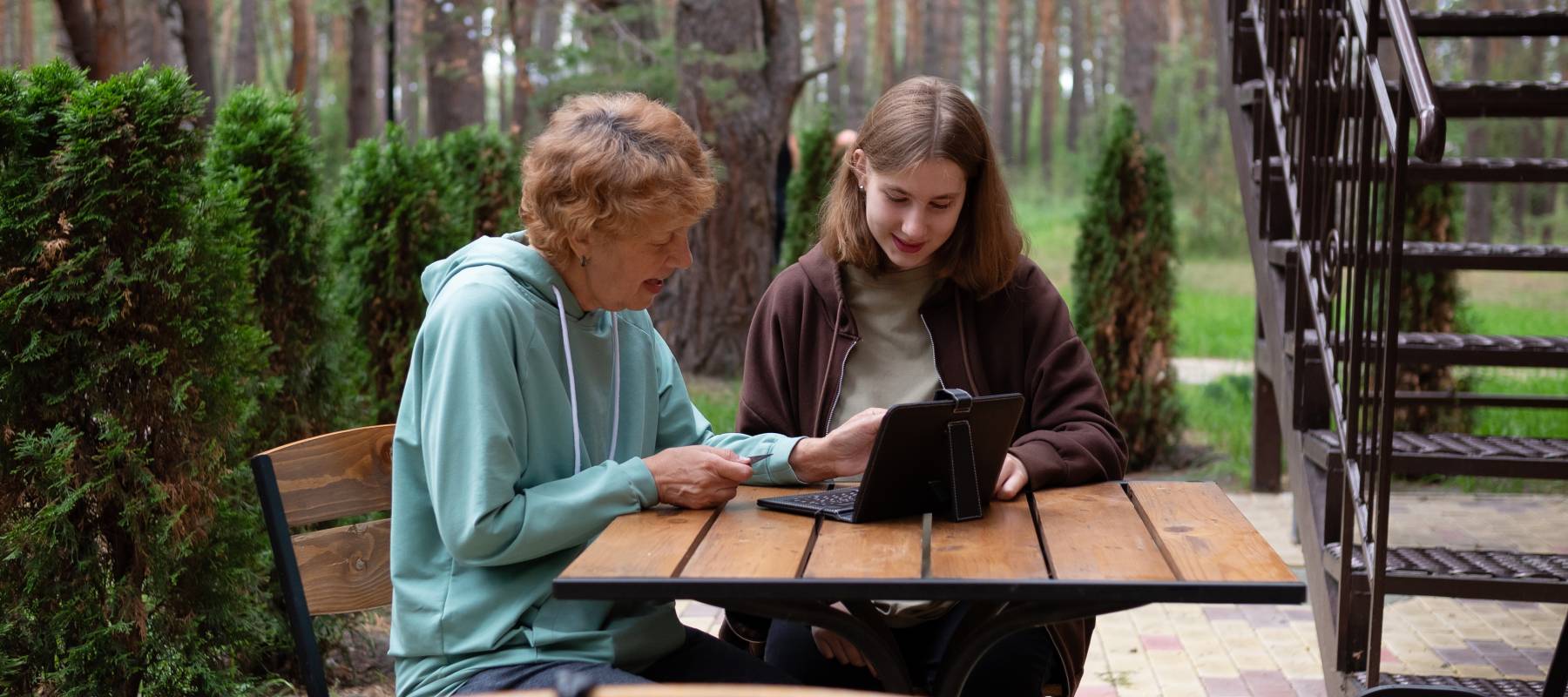 happy teenage girl teaches older 70s grandmothers to use a laptop at home
