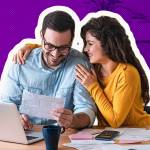 Positive young couple embracing and paying household bills or taxes on laptop online at home