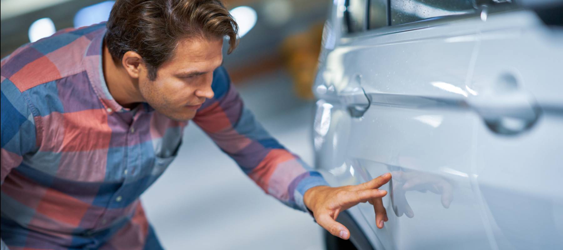Man inspecting scratch on a car.