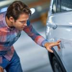 Man inspecting scratch on a car.