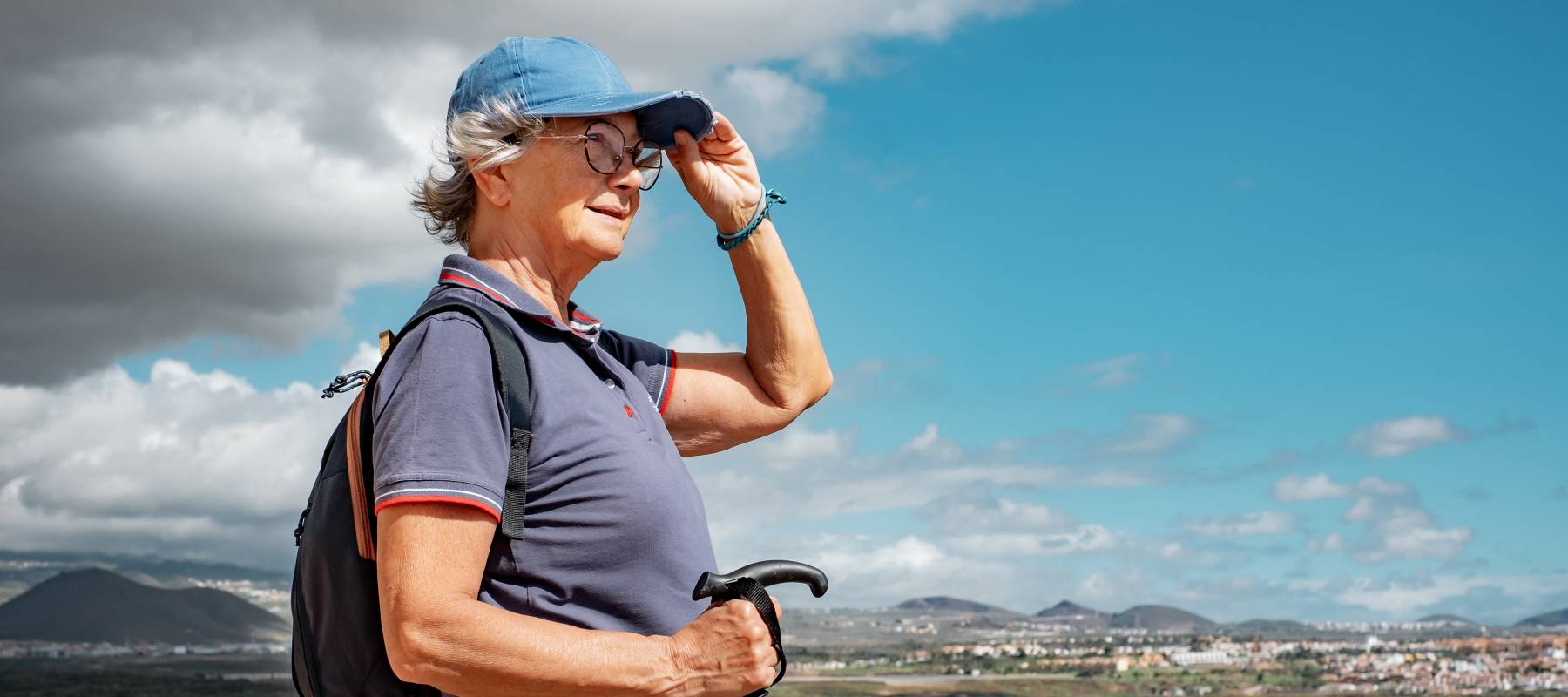 senior Caucasian woman walking on hiking day on outdoor trail on excursion between sea and countryside