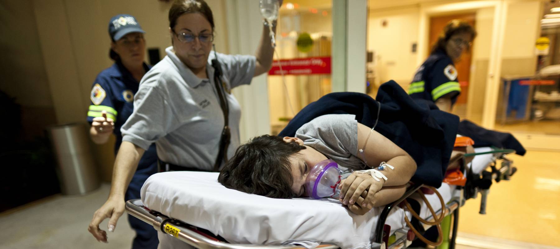 Child in emergency room being rolled on a stretcher by emergency crew.