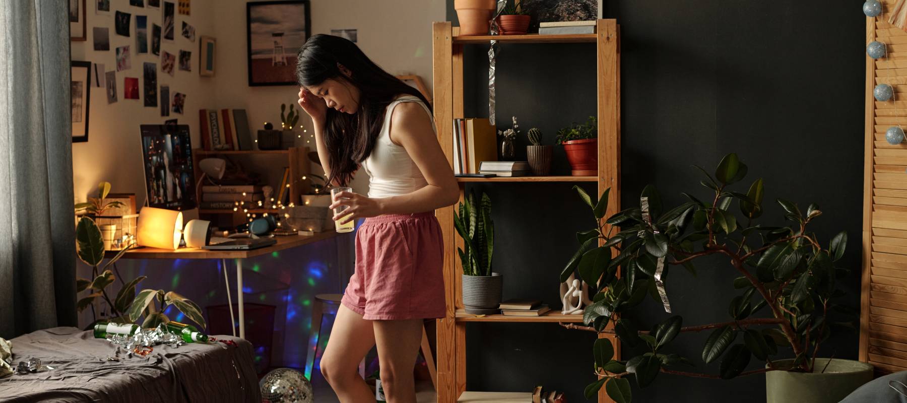 Woman looking stressed in messy room with decorations piled up on floor.