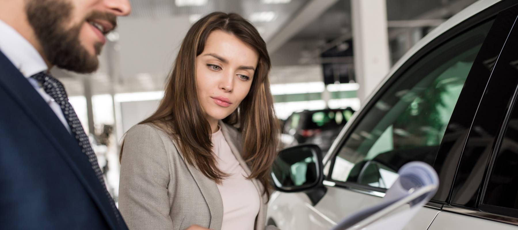 Woman looking at paperwork at car dealership.