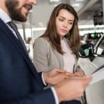 Woman looking at paperwork at car dealership.