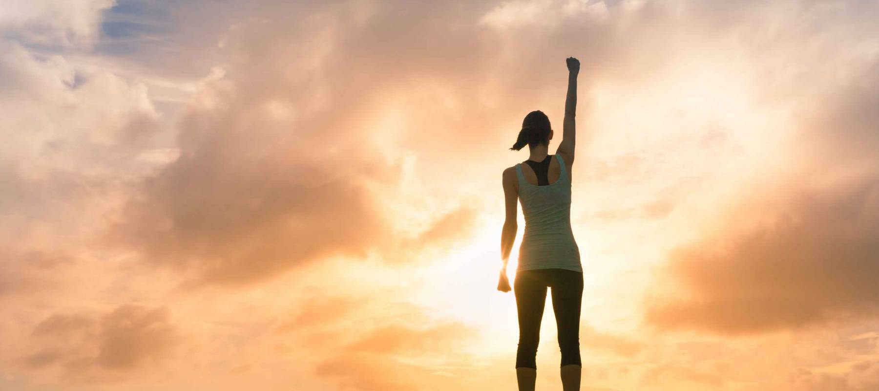 Young female celebrating victory on top a mountain.