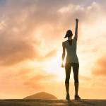 Young female celebrating victory on top a mountain.