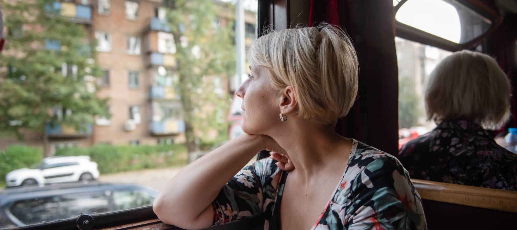 Middle-aged woman looking out of a train window, deep in thought.