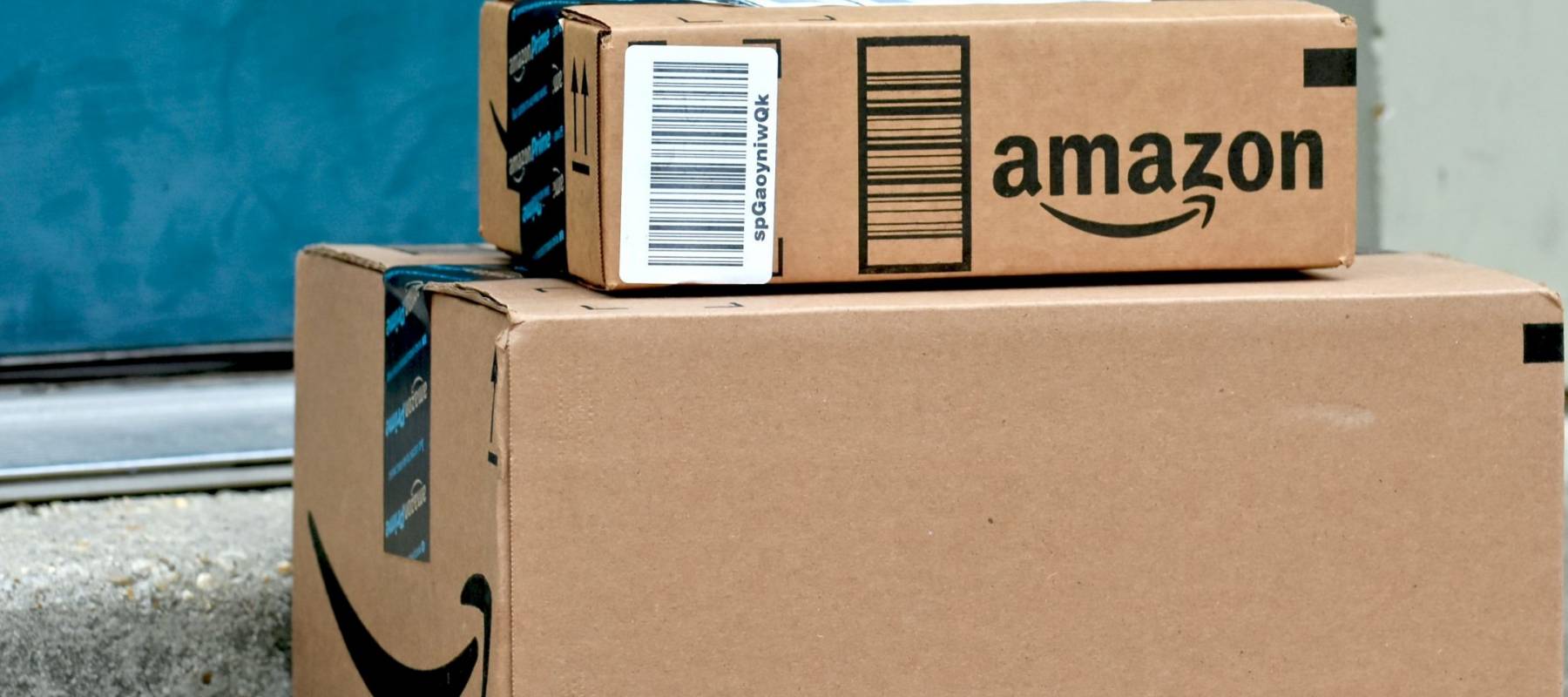 PARIS, FRANCE - JAN 28, 2016: Amazon logotype printed on cardboard box side, seen from above on a wooden floor. Amazon Inc is the an American electronic e-commerce company