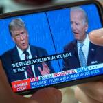 A man uses his cellphone to watch a debate between US President Donald Trump and Democratic presidential candidate and former Vice President Joe Biden.