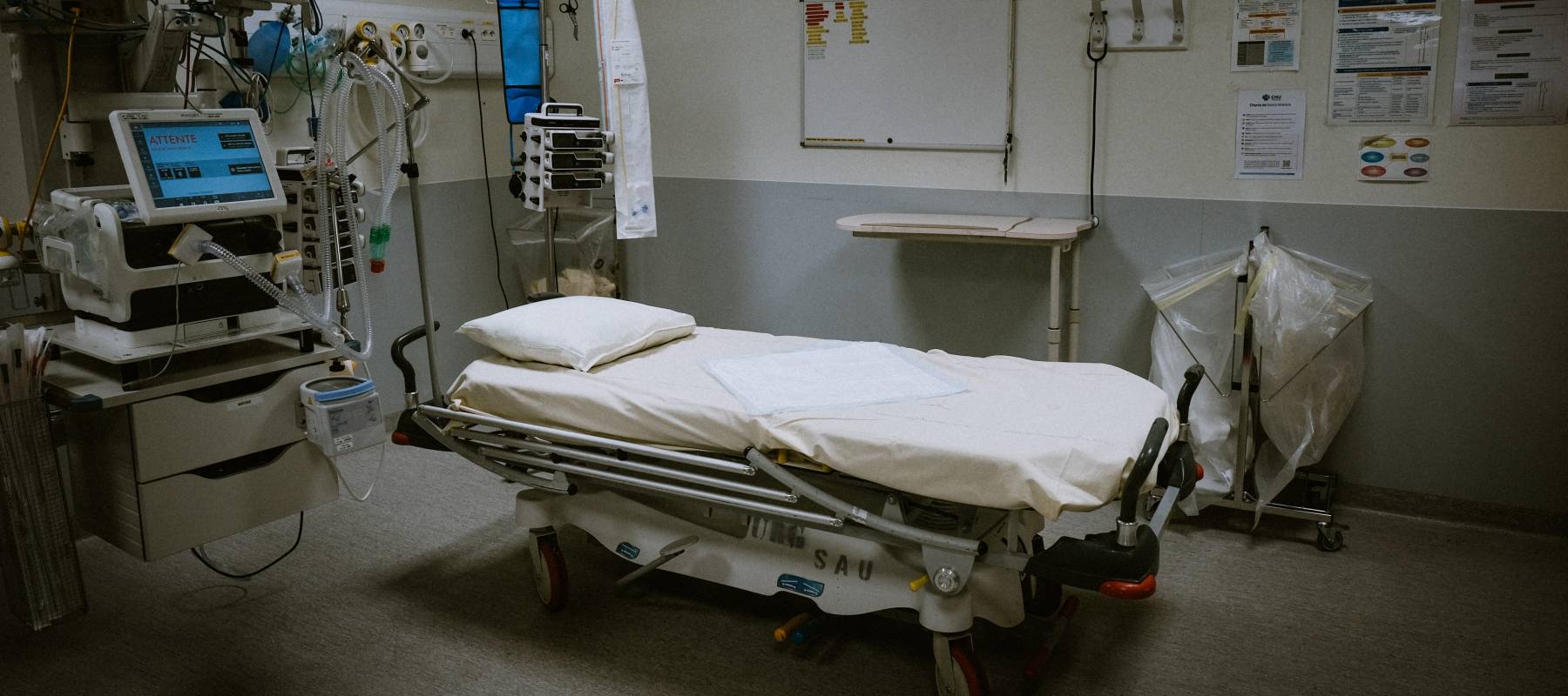 Room with empty bed and respiratory assistance equipment.