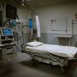 Room with empty bed and respiratory assistance equipment.
