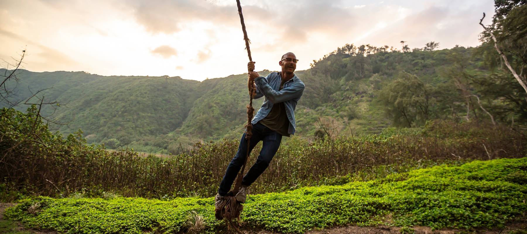 Middle-aged adult male swinging on a rope swing.