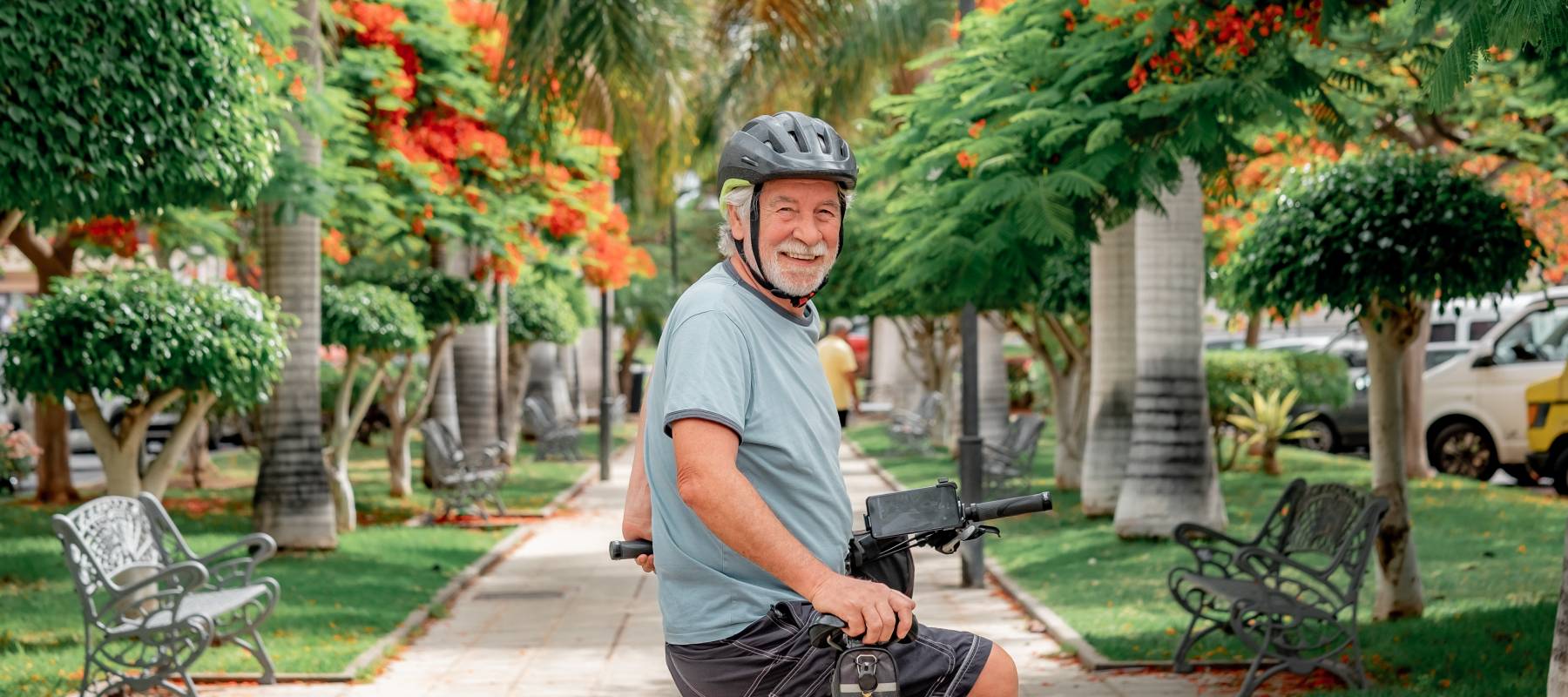 happy Caucasian senior cyclist man with helmet riding his electric bike in the city